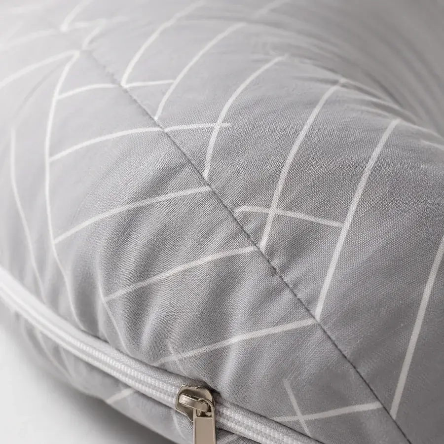 Gros plan sur la couture et la fermeture à glissière du coussin, tissu gris à fins chevrons blancs