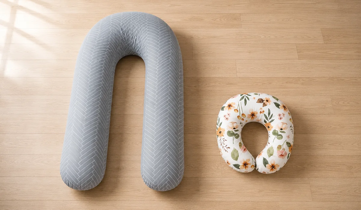 Les deux coussins Berceline côte à côte sur un parquet : le grand U de grossesse gris à gauche, le coussin d’allaitement compact à motif floral à droite