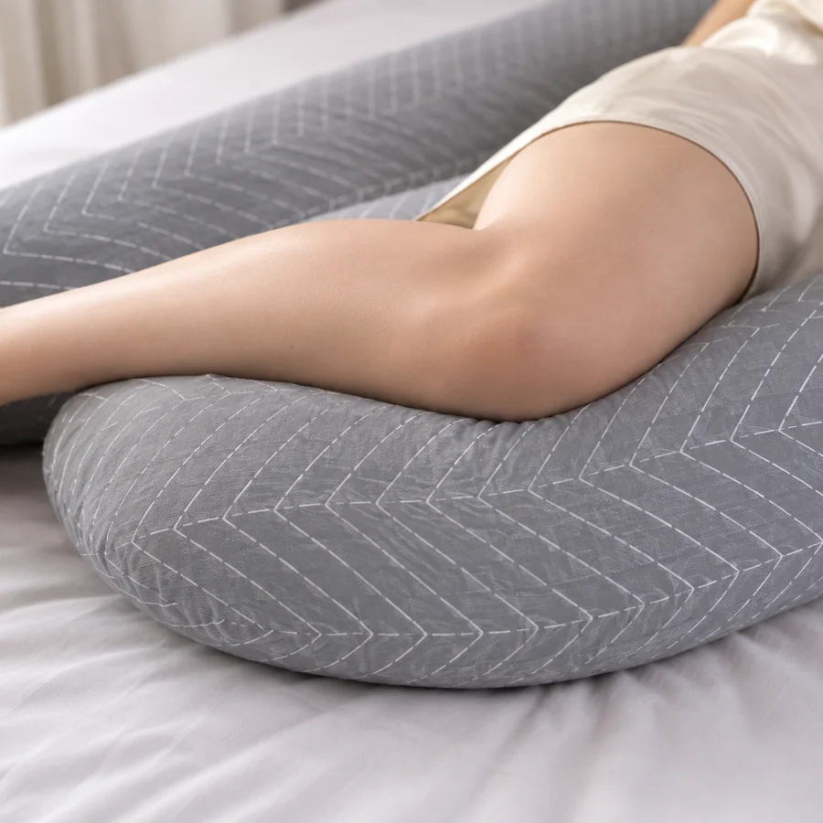 Détail d’un genou replié reposant sur la branche du coussin de grossesse Berceline, la cuisse à l’horizontale