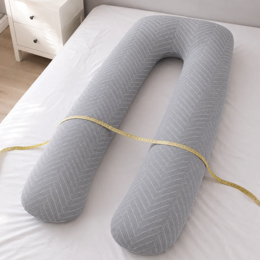 Mètre ruban souple posé en travers du coussin de grossesse en U sur un lit