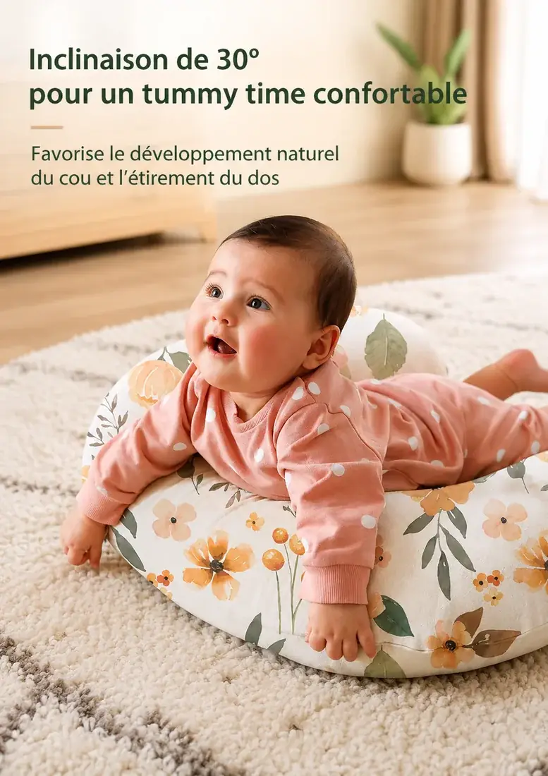 Un nourrisson sur le ventre, les bras posés sur le coussin d’allaitement à motif floral, sur un tapis